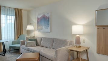 Une chambre d’hôtel avec un canapé, une petite table, une lampe et un tableau au mur.
