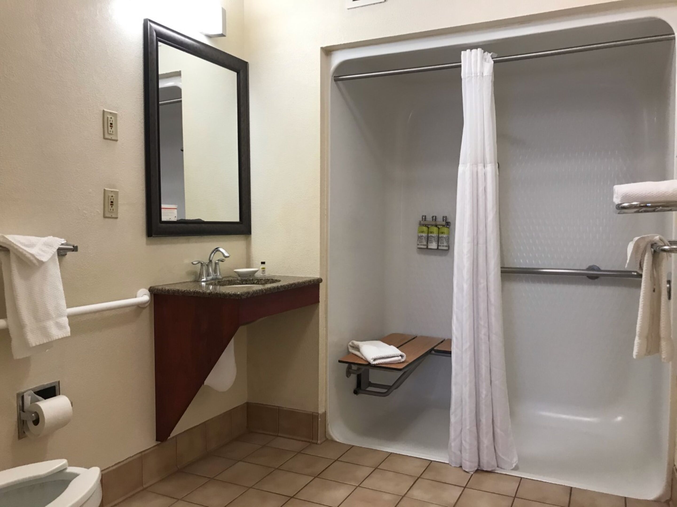 Ein Badezimmer mit Waschbecken, Spiegel, Toilette und Duschkabine.