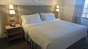 A hotel room with a large bed, two bedside tables with lamps, a telephone, and artwork on the wall.