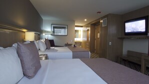 A hotel room with two beds, a television, a bathroom, and a hallway.