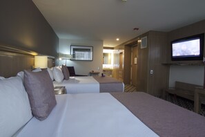 Una habitaci ón de hotel con dos camas, televisión, baño y un pasillo.