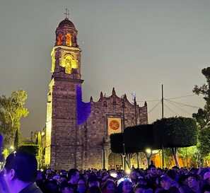 Un edificio histórico con una imponente torre de reloj, rodeado de gente.