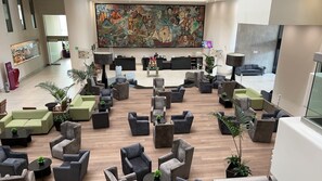 A spacious lobby with multiple seating areas, a large mural on the wall, and a reception desk.