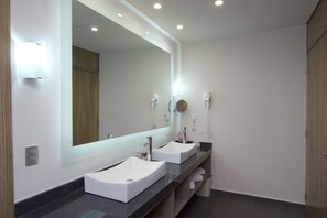 Un baño moderno con dos lavamanos, un espejo grande y un secador de pelo en la pared.