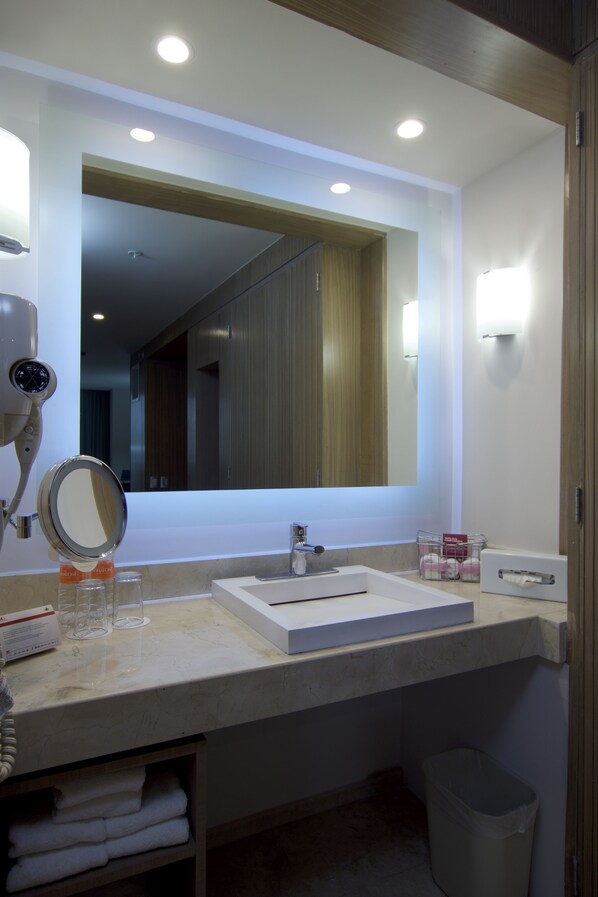 A modern bathroom with a large mirror, a sink, and a hairdryer.