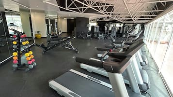 A gym with treadmills, weight machines, and a rack of dumbbells.