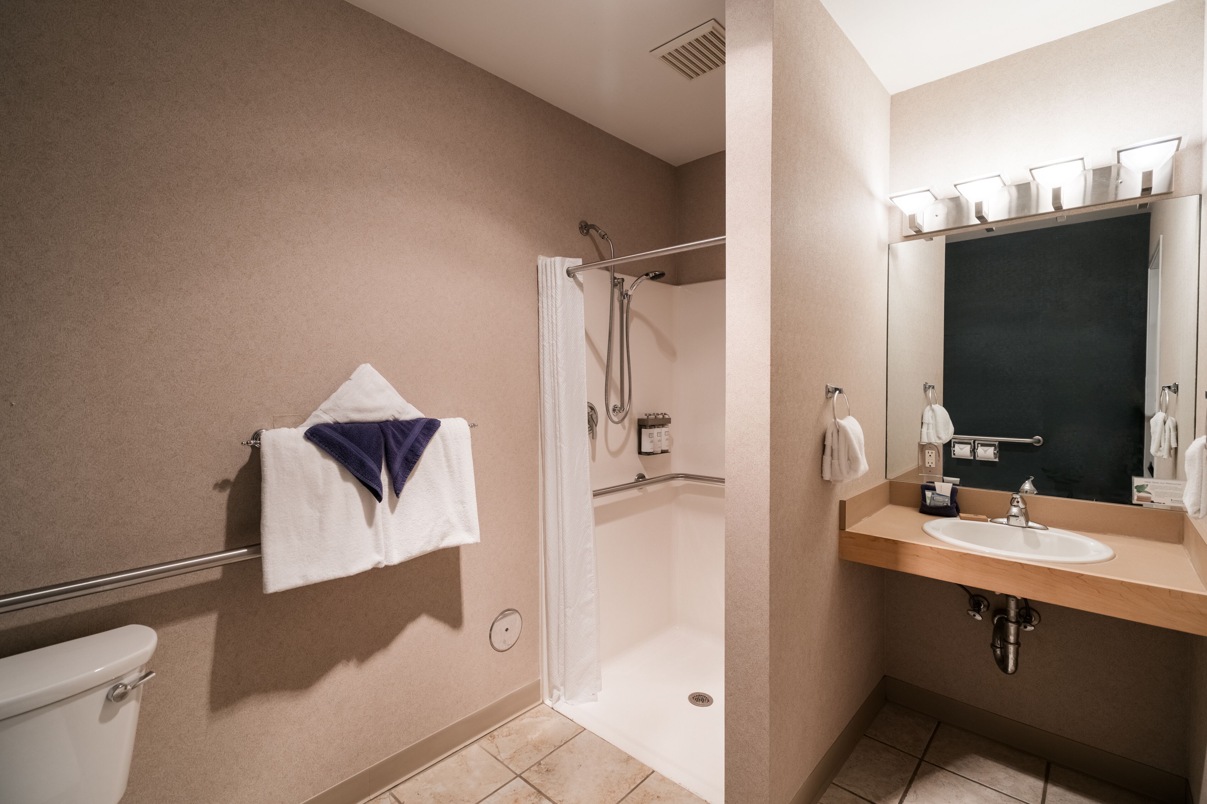 Ein Badezimmer mit Dusche, Toilette, Waschbecken und Spiegel.