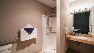 Ein Badezimmer mit Dusche, Toilette, Waschbecken und Spiegel.