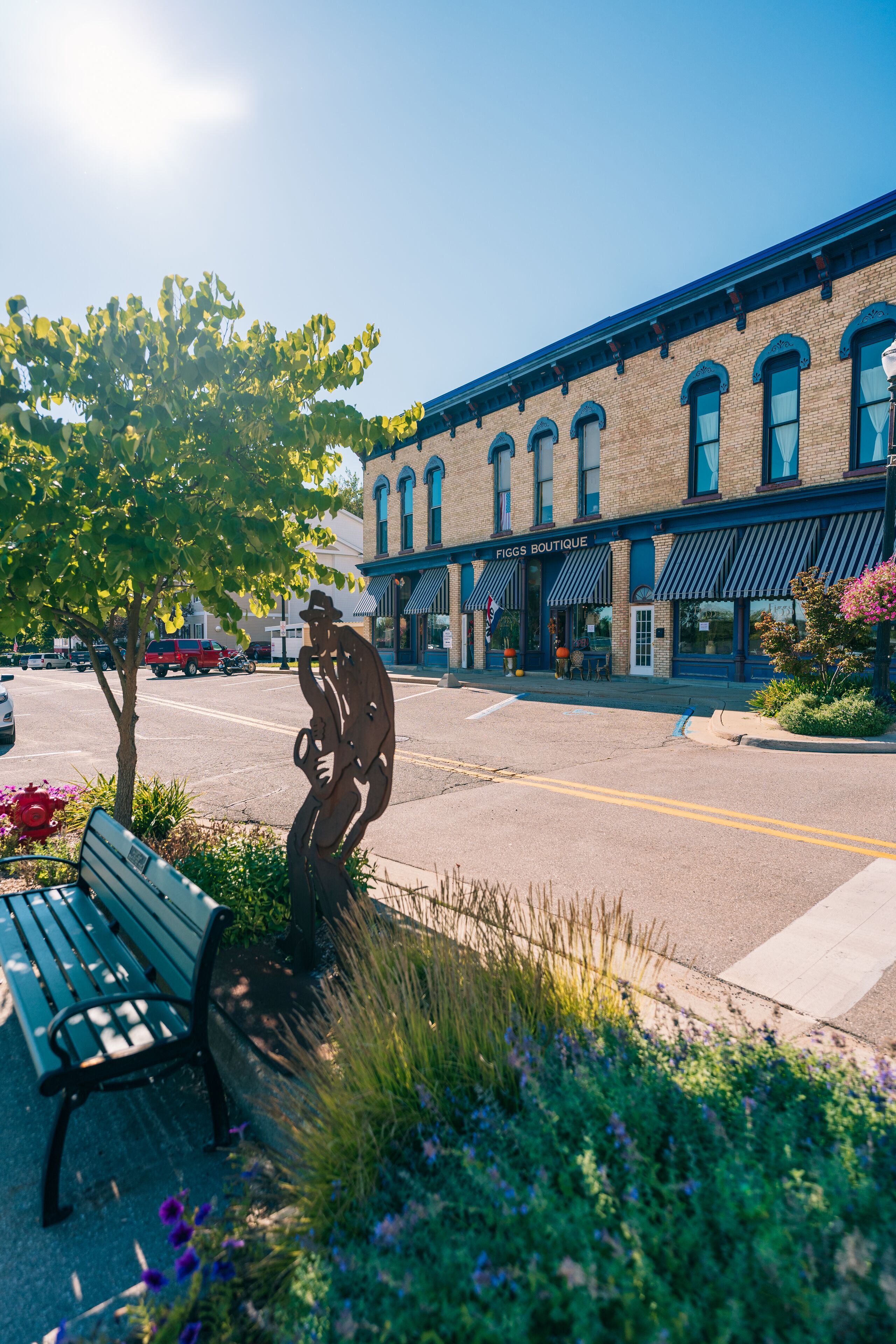 A street scene with a bench, a statue, and a building labeled "FIGGS BOUTIQUE".