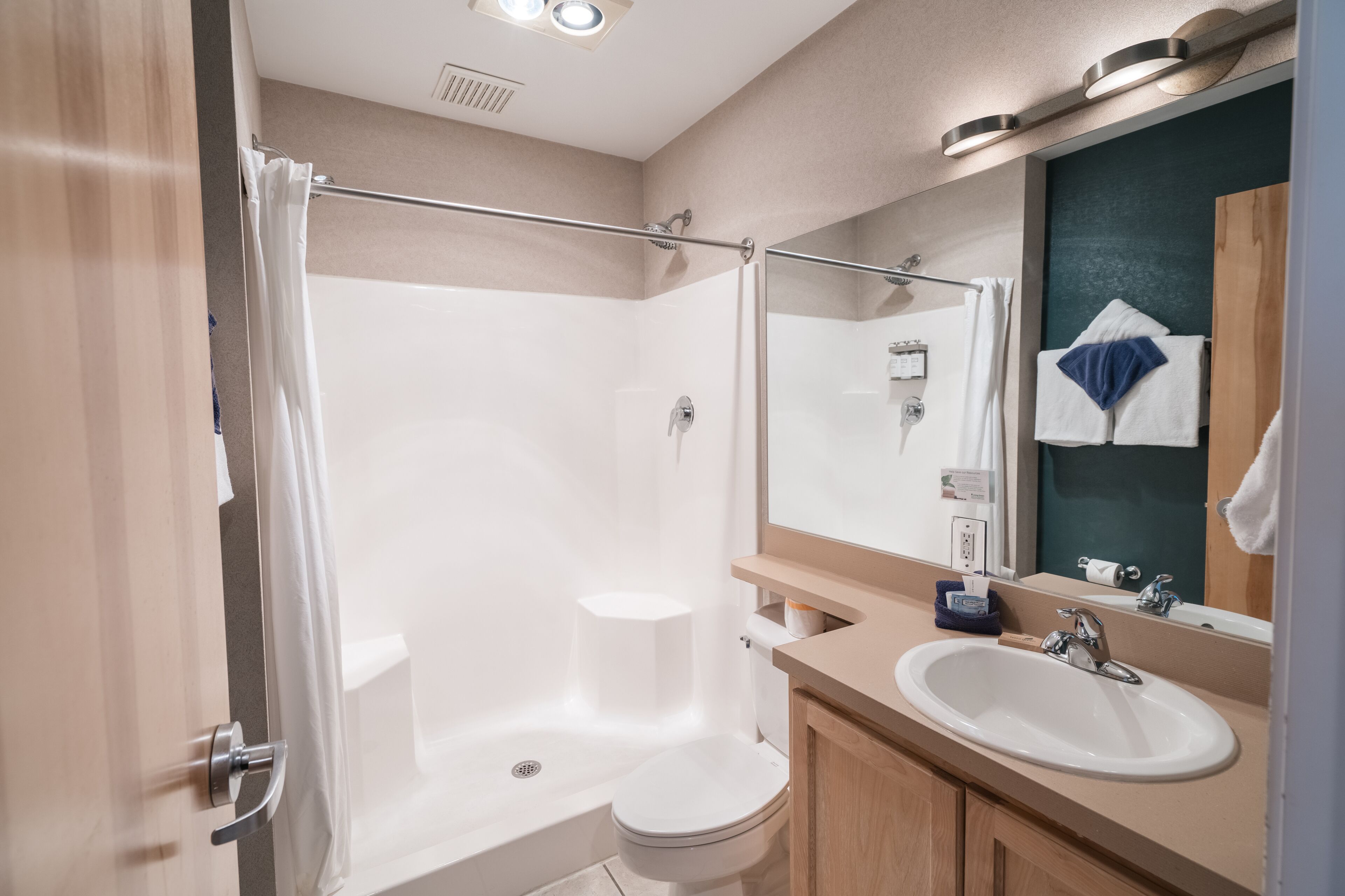 A modern bathroom with a shower, toilet, sink, and a mirror.