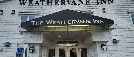 The exterior of The WeatherVane Inn, featuring a prominent entrance with a black awning and a handicap parking sign.