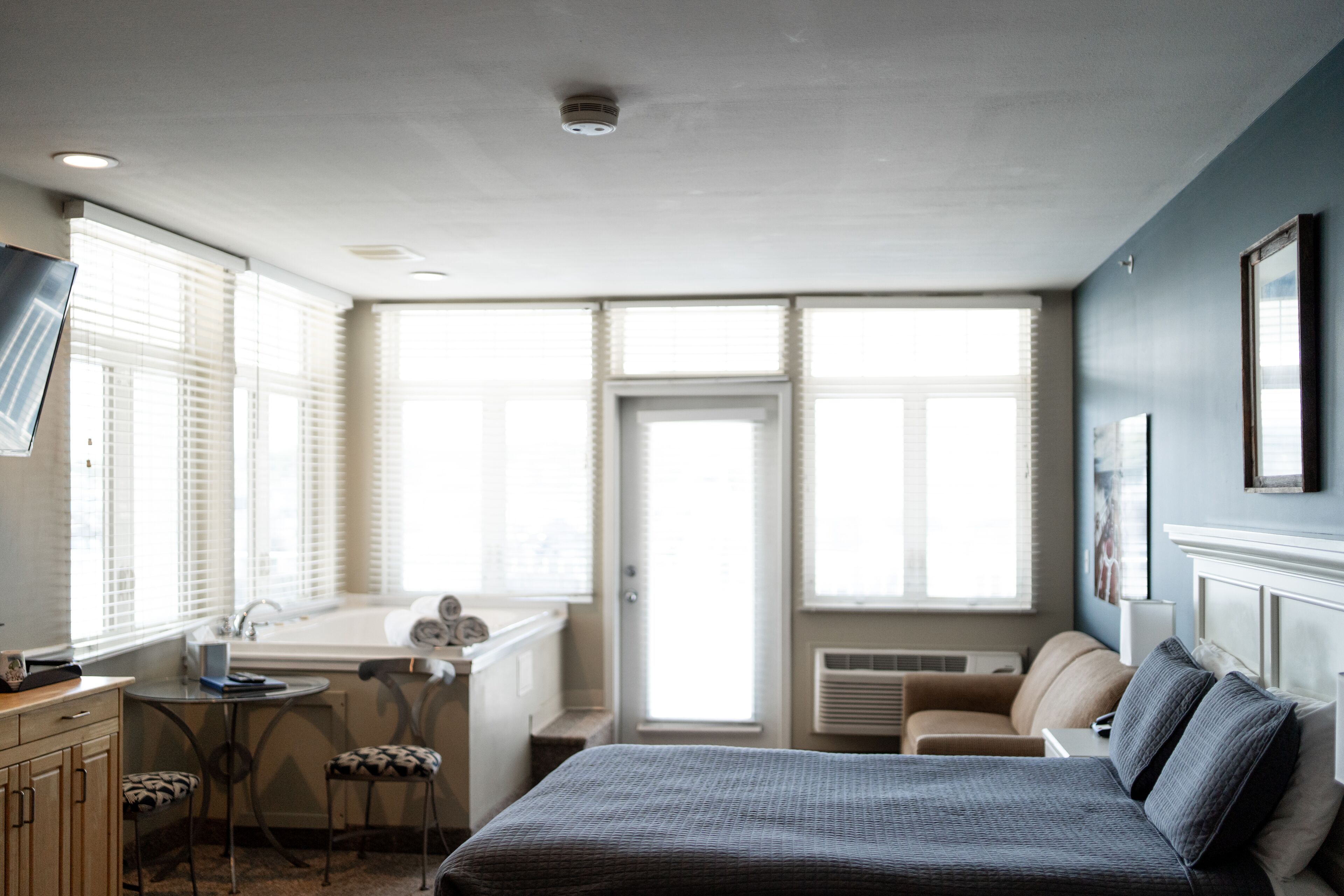 Un dormitorio con cama, escritorio, silla y ventana.
