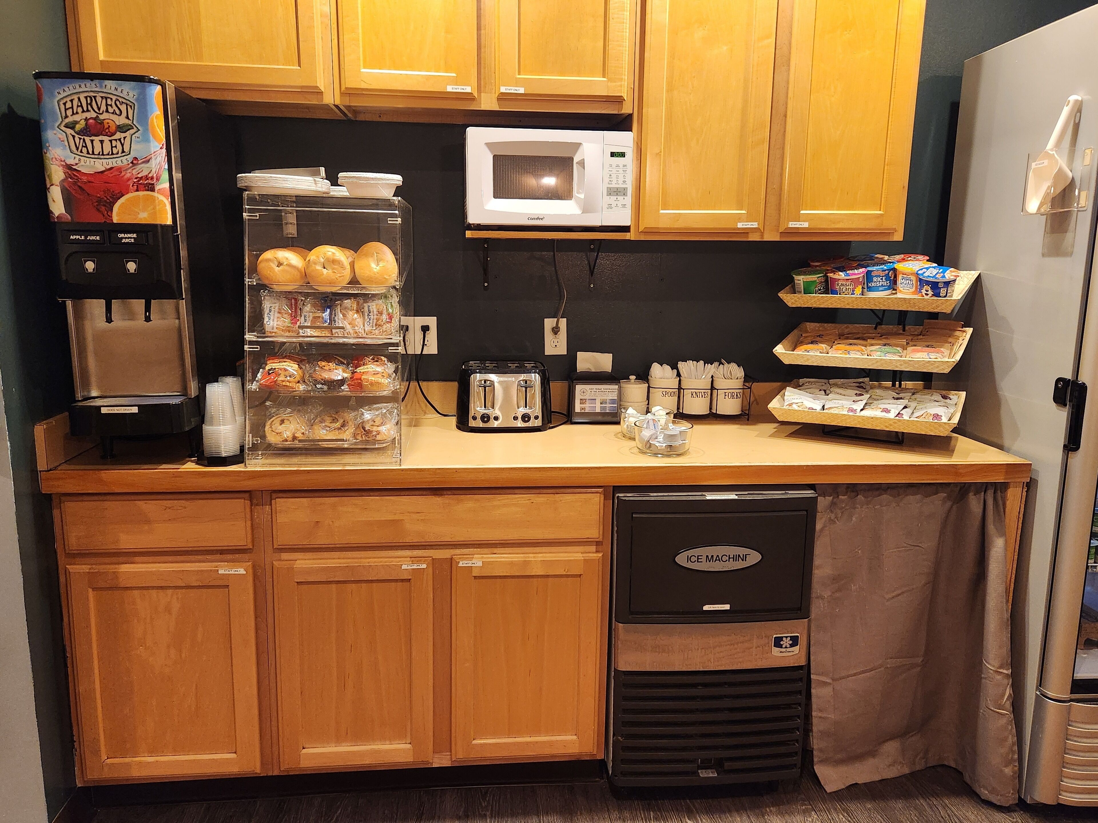 A kitchen with wooden cabinets, a coffee machine, a microwave, a toaster, and a dishwashing machine.