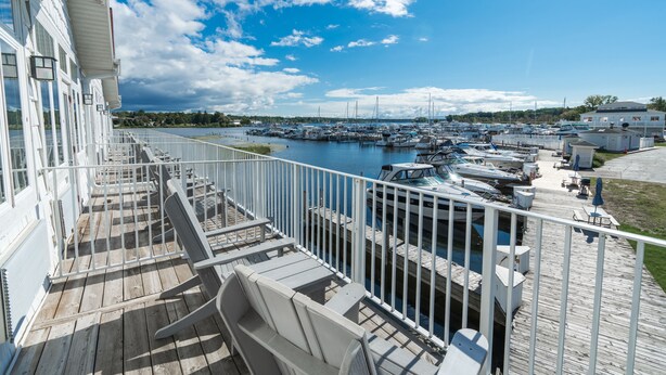 A marina with boats docked, a wooden deck with seating, and a view of the water. - The Weathervane Inn (Montague)
