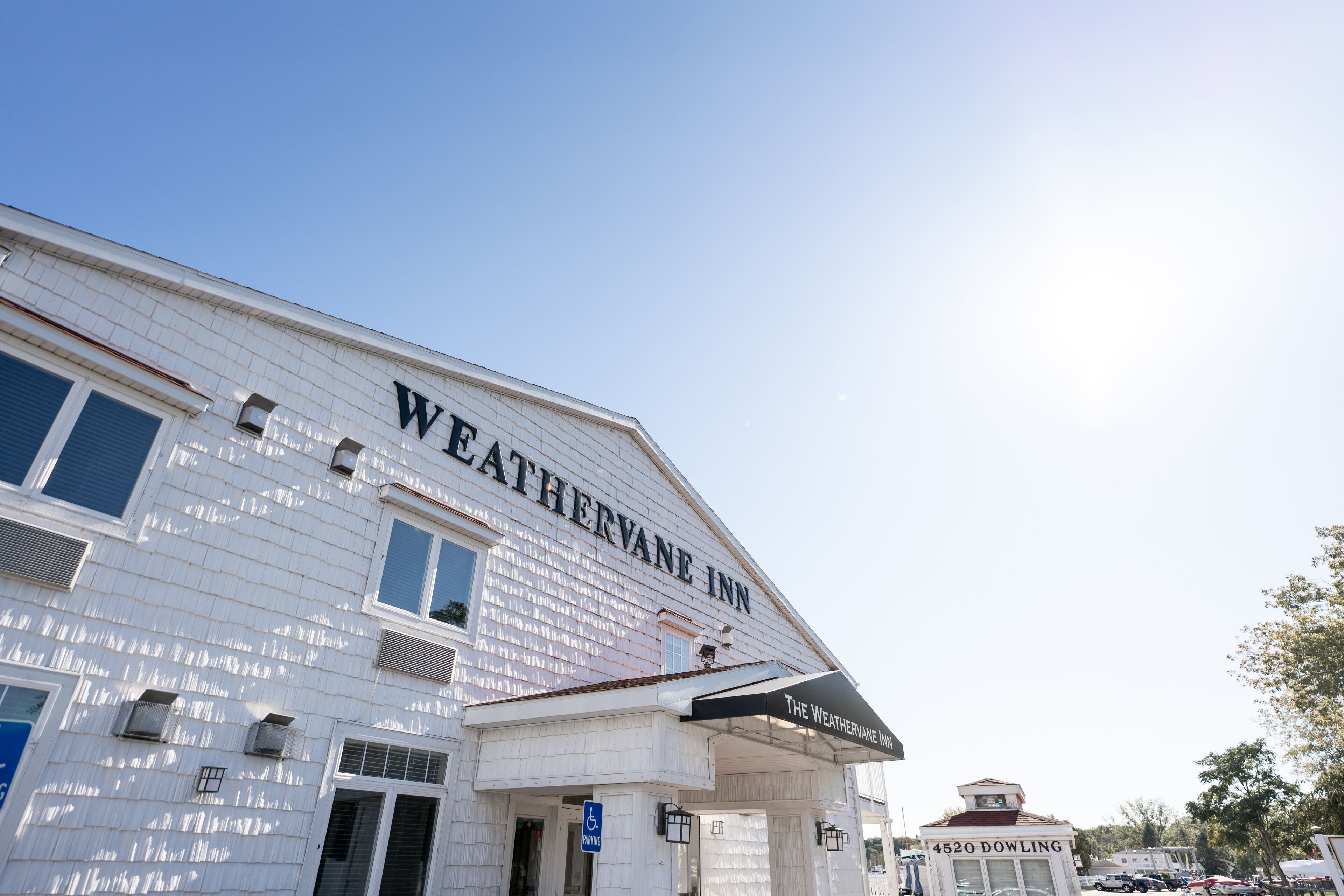 Un edificio con el letrero "WEATHERVANE INN" y "4520 DOWLING" en su fachada.
