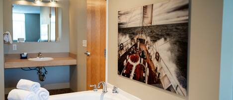 Un baño con una bañera grande, un lavabo, un espejo y una puerta.