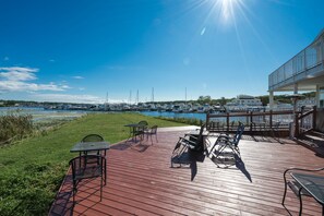 A wooden deck with outdoor seating, overlooking a marina with boats.
