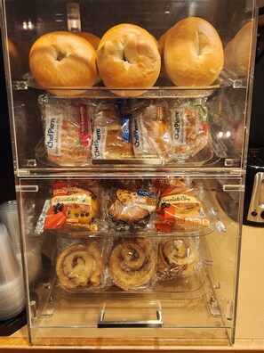 A bakery display case with various baked goods including bagels, bread, muffins, and pastries.