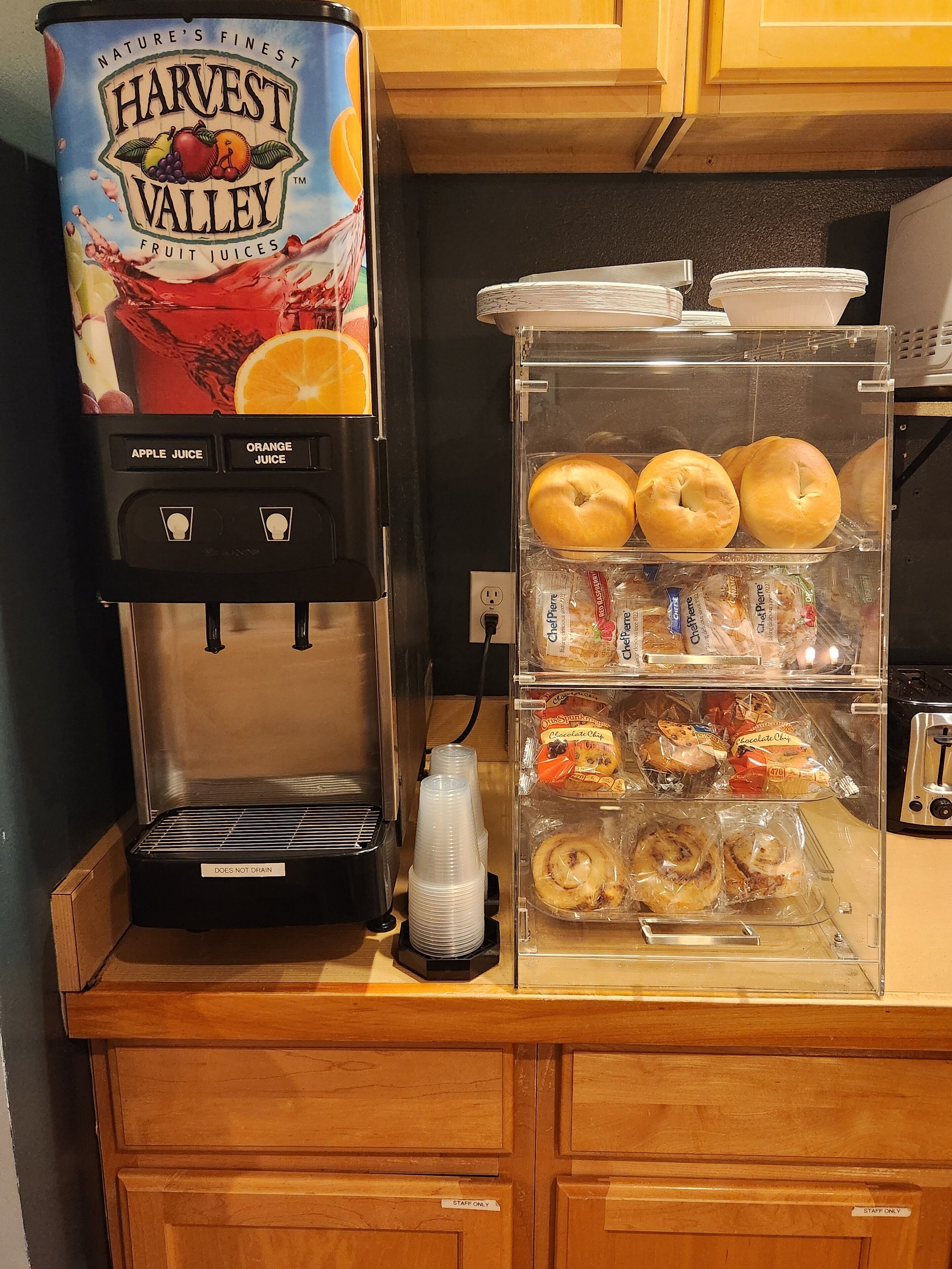 A coffee machine with a label reading "Harvest Valley Fruit Juices" and a refrigerated display case with various pastries.