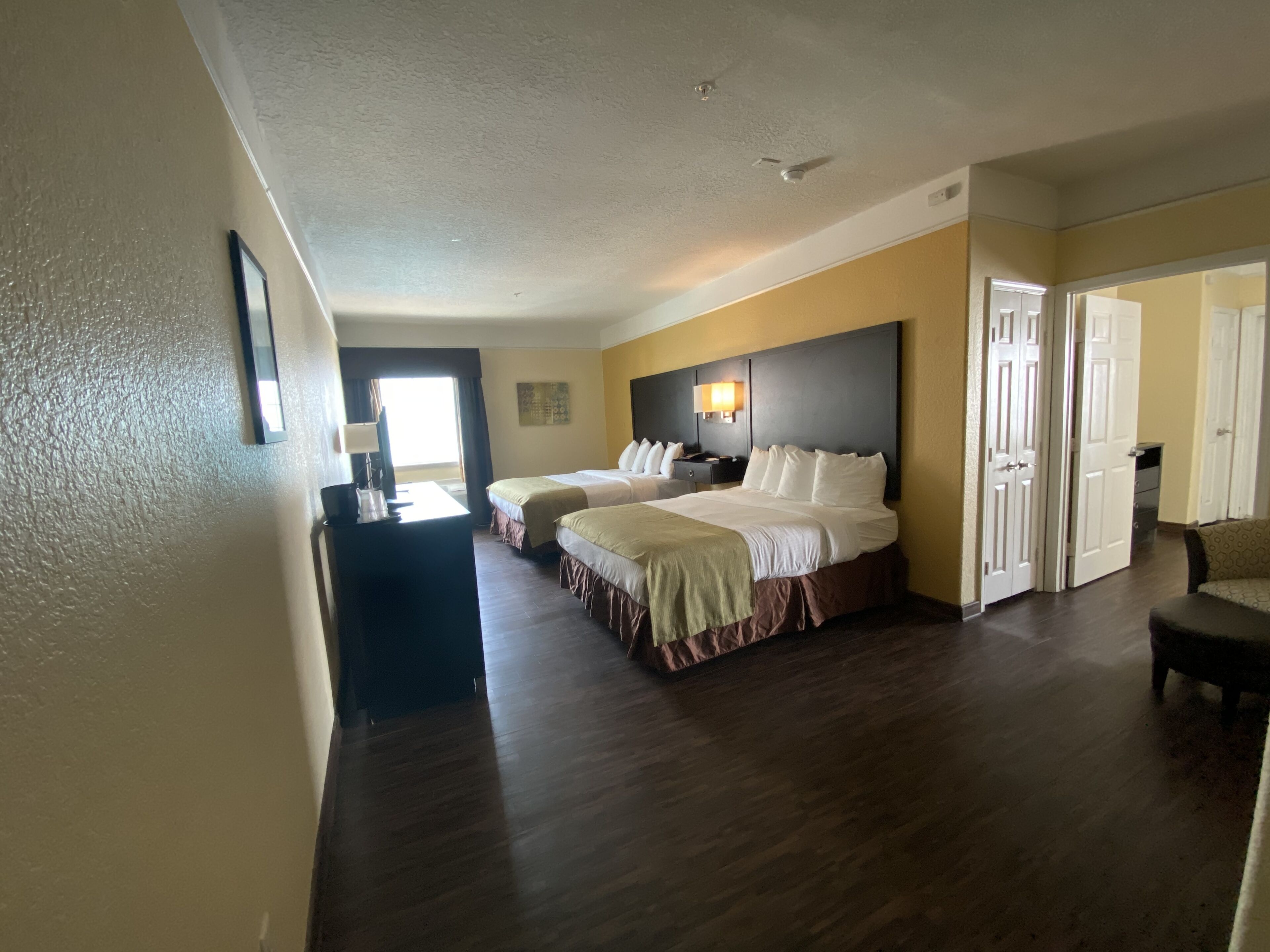 A hotel room with two beds, a desk, and a chair.