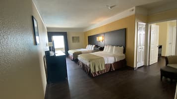 A hotel room with two beds, a desk, and a chair.