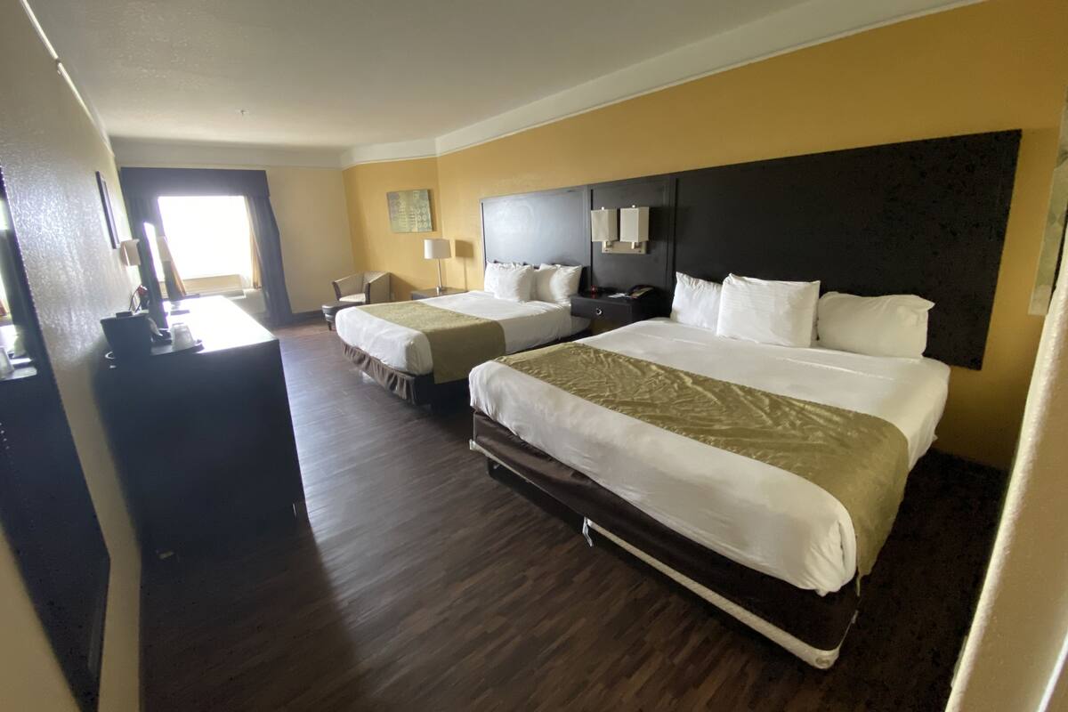 A hotel room with two beds, a desk, and a chair.