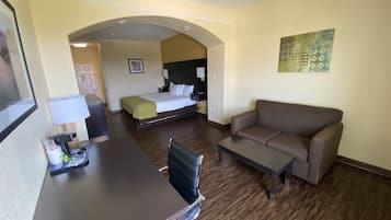 A hotel room with a bed, a sofa, a desk, and a chair.