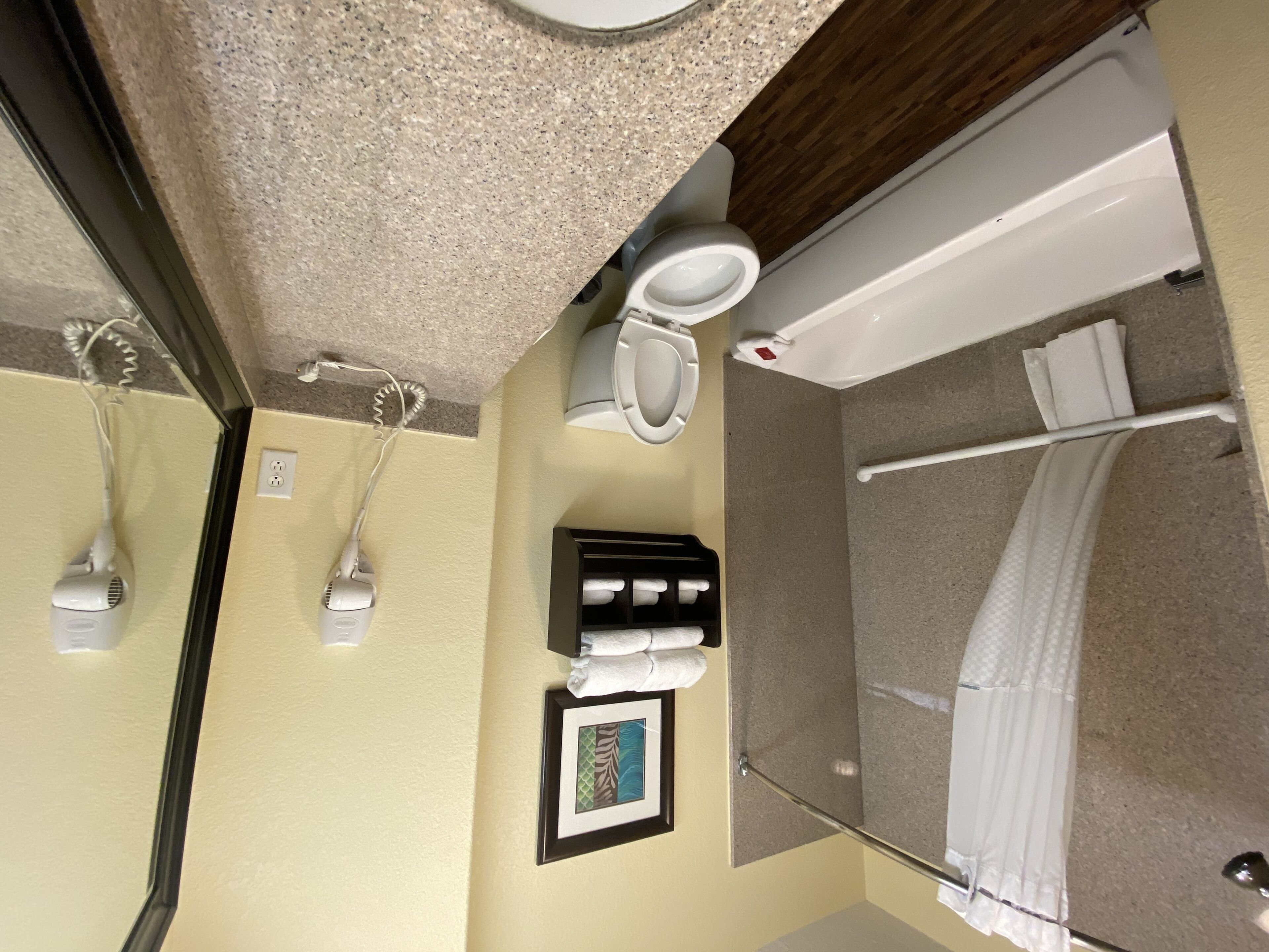 Une salle de bain comprenant des toilettes, un lavabo, un miroir, une douche et un porte-serviettes.