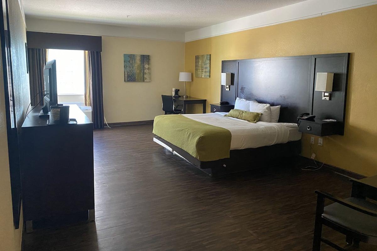 A hotel room with a large bed, a desk with a computer, a chair, and a television.
