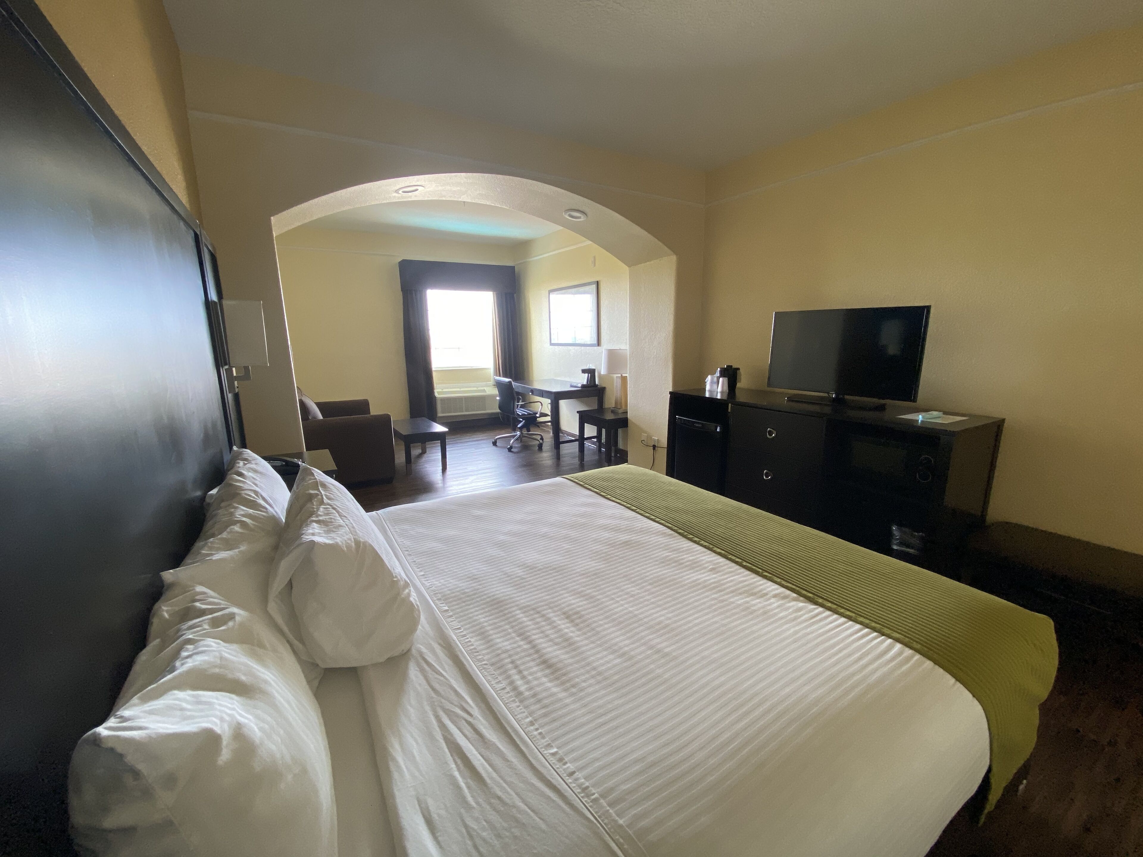 A hotel room with a bed, a desk, a chair, a television, and a wardrobe.