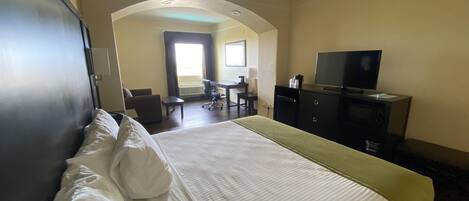 A hotel room with a bed, a desk, a chair, a television, and a wardrobe.