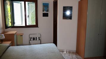 Una camera da letto con un letto, un armadio, una scrivania, una sedia e una finestra con tende.