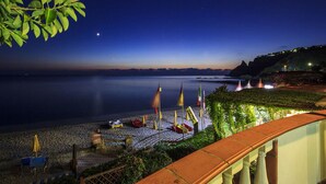 A beachside view with a calm sea, umbrellas, and a clear night sky. - Hotel Village Eden (Ricadi)