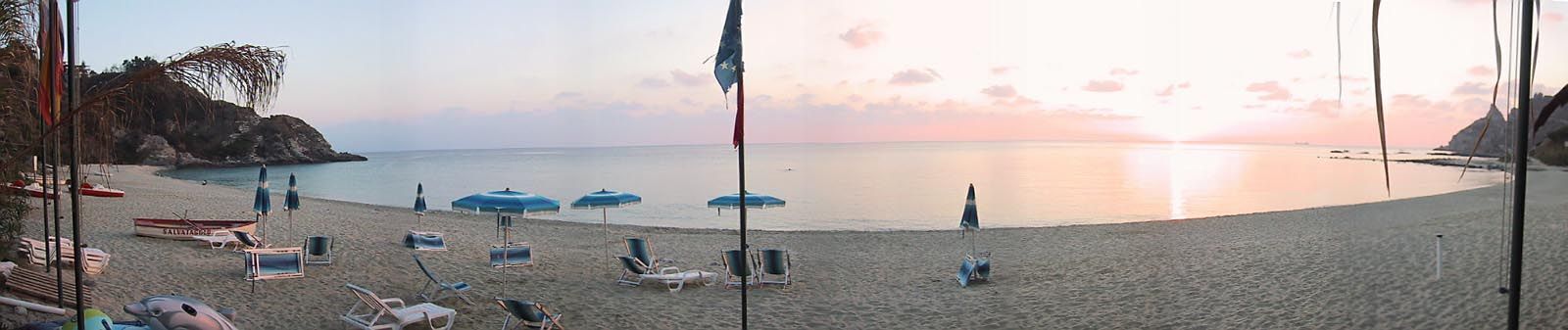 A beach with umbrellas and lounge chairs.