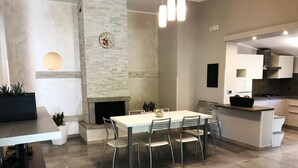 A modern kitchen with a dining area, featuring a built-in stove, white cabinets, and a large island with a black countertop. - Hotel Village Eden (Ricadi)
