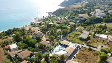 Stunning coastal homes surround a resort-style pool, offering breathtaking views of the sea.