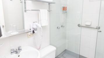 A modern bathroom with a glass-enclosed shower, a white sink, and a toilet.