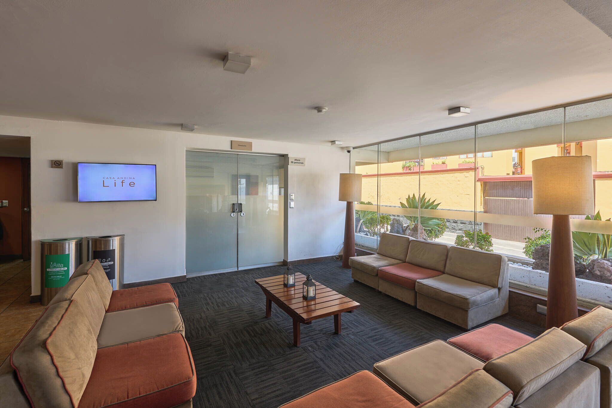 A lobby with a television, seating area, and a glass wall with a view.