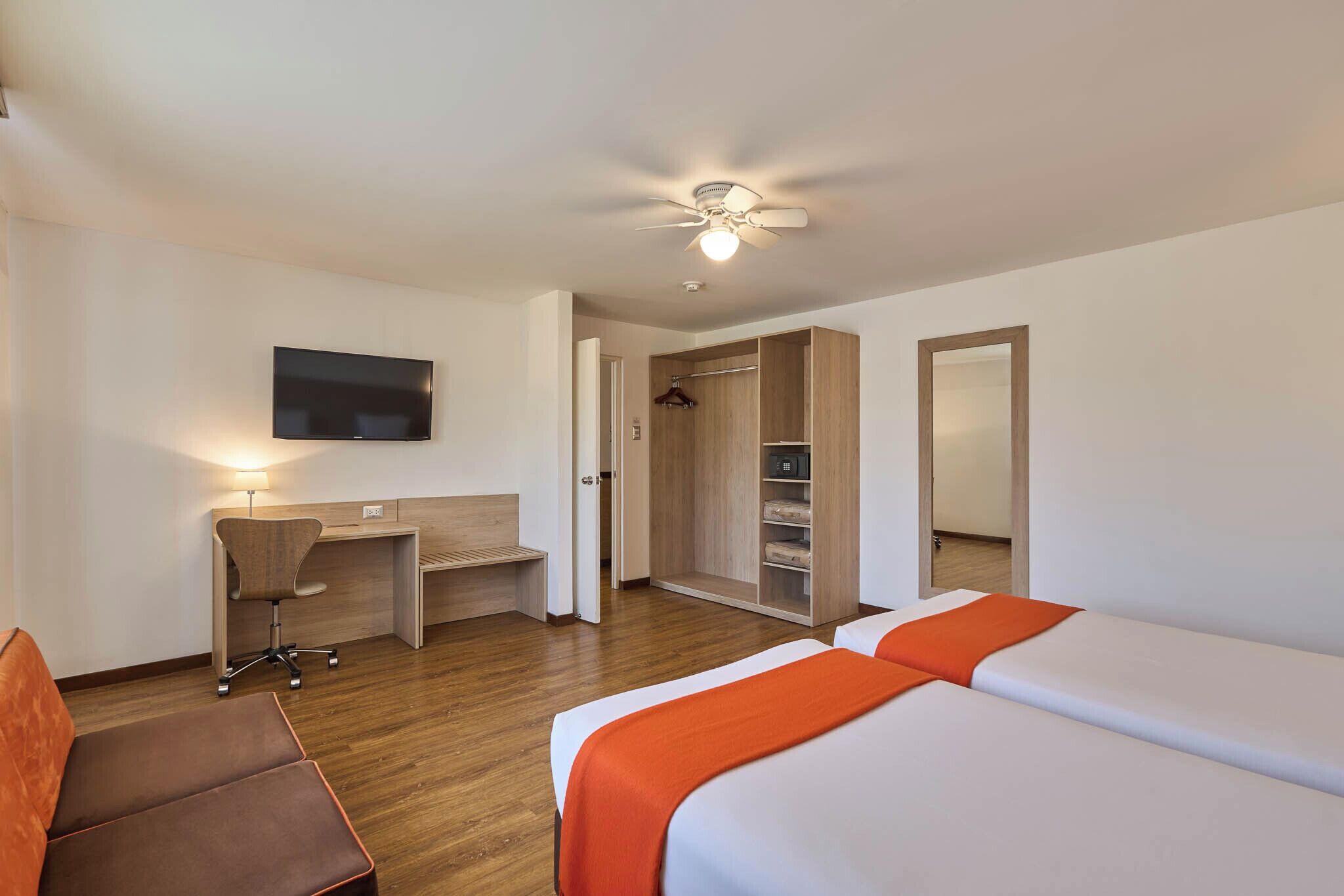 Een hotelkamer met een bed, bureau, stoel, kledingkast en een televisie.