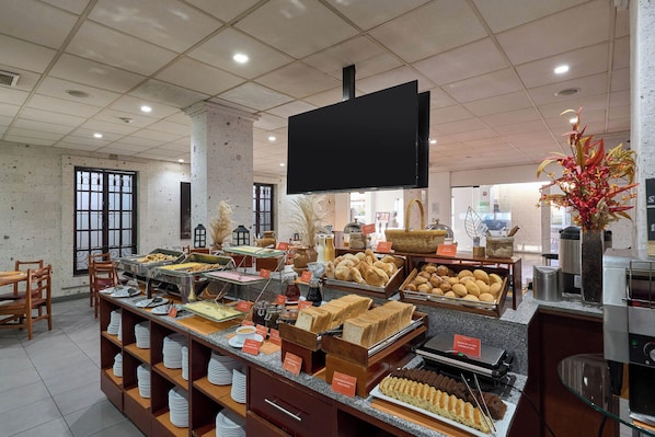 A buffet area with various food items, a flat-screen TV, and a decorative plant.