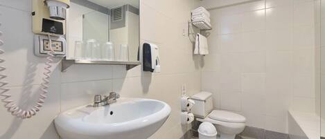 A bathroom with a sink, toilet, hand dryer, and a mirror.
