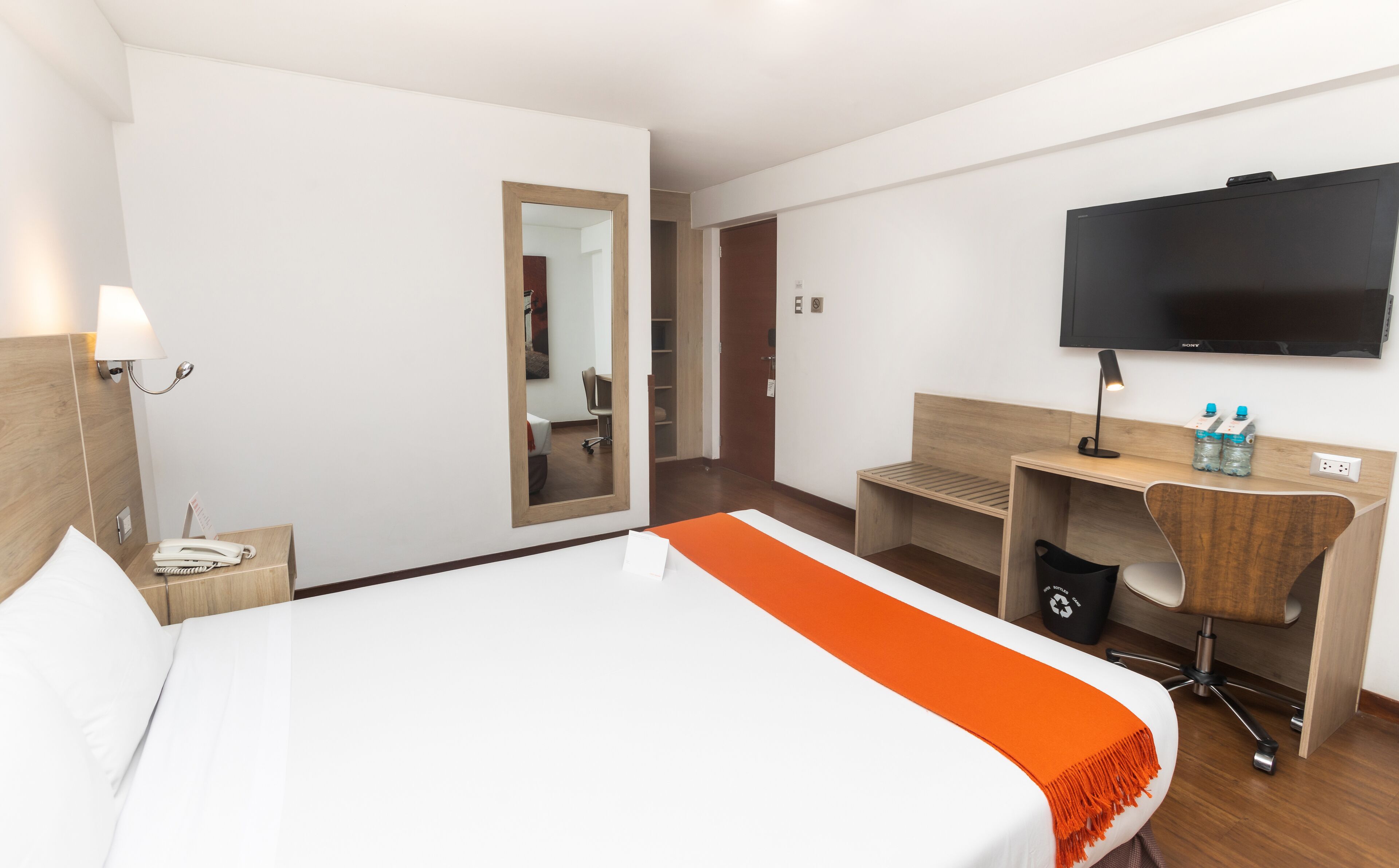 Une chambre d’hôtel équipée d’un lit, d’un bureau, d’une chaise, d’une télévision, d’un téléphone et d’un miroir.