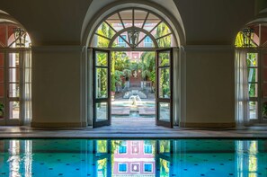 A pool area with a view of a fountain and a building in the background.