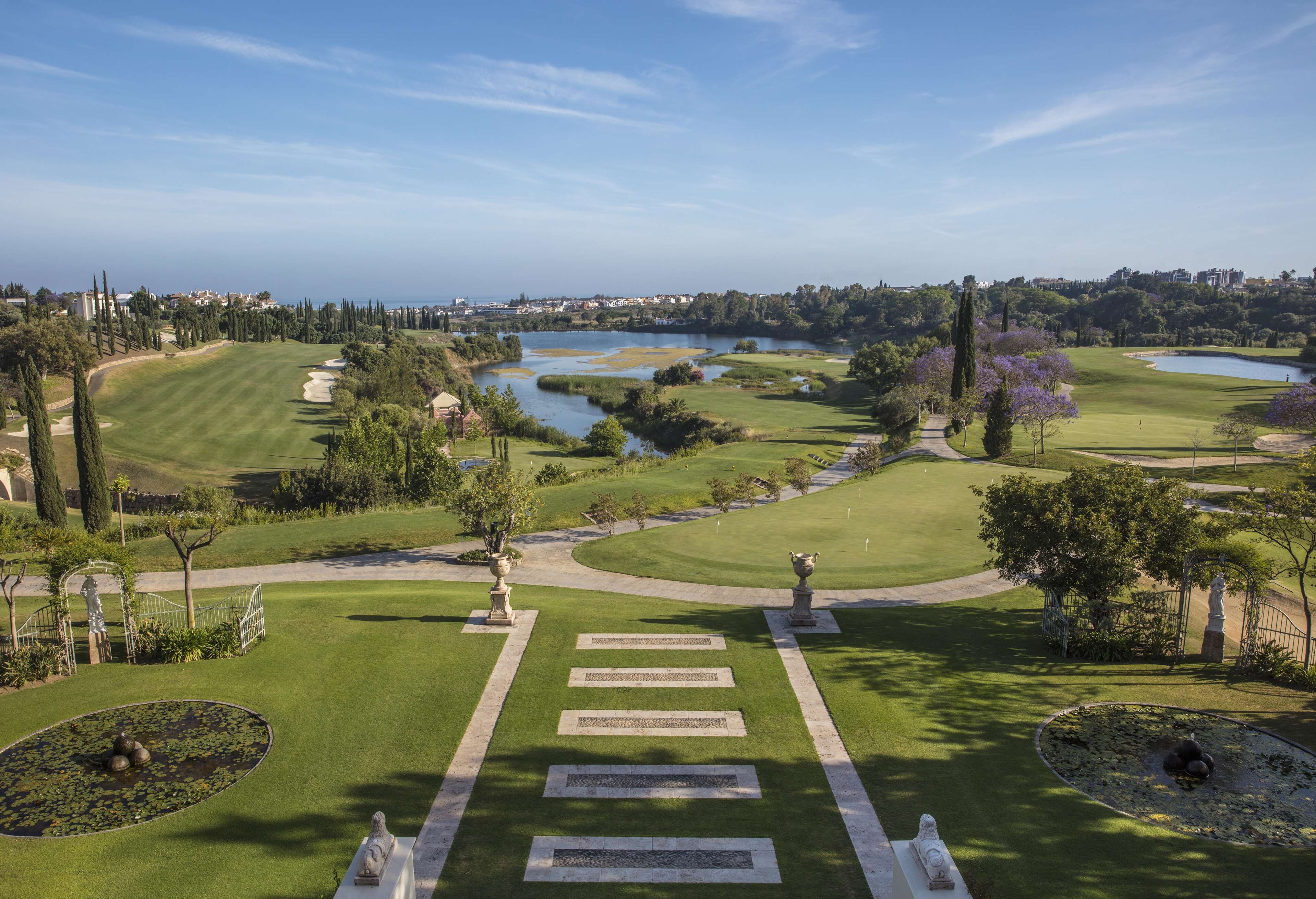 Un parcours de golf agrémenté d’un étang, de statues et offrant une vue dégagée sur le paysage environnant.