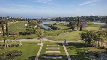 A golf course with a pond, statues, and a clear view of the surrounding landscape.