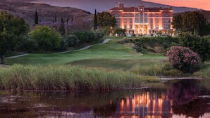 A large, multi-story building with a well-maintained lawn and a pond in the foreground. - Anantara Villa Padierna Palace Benahavís Marbella Resort - A Leading hotel of the world (Benahavis)