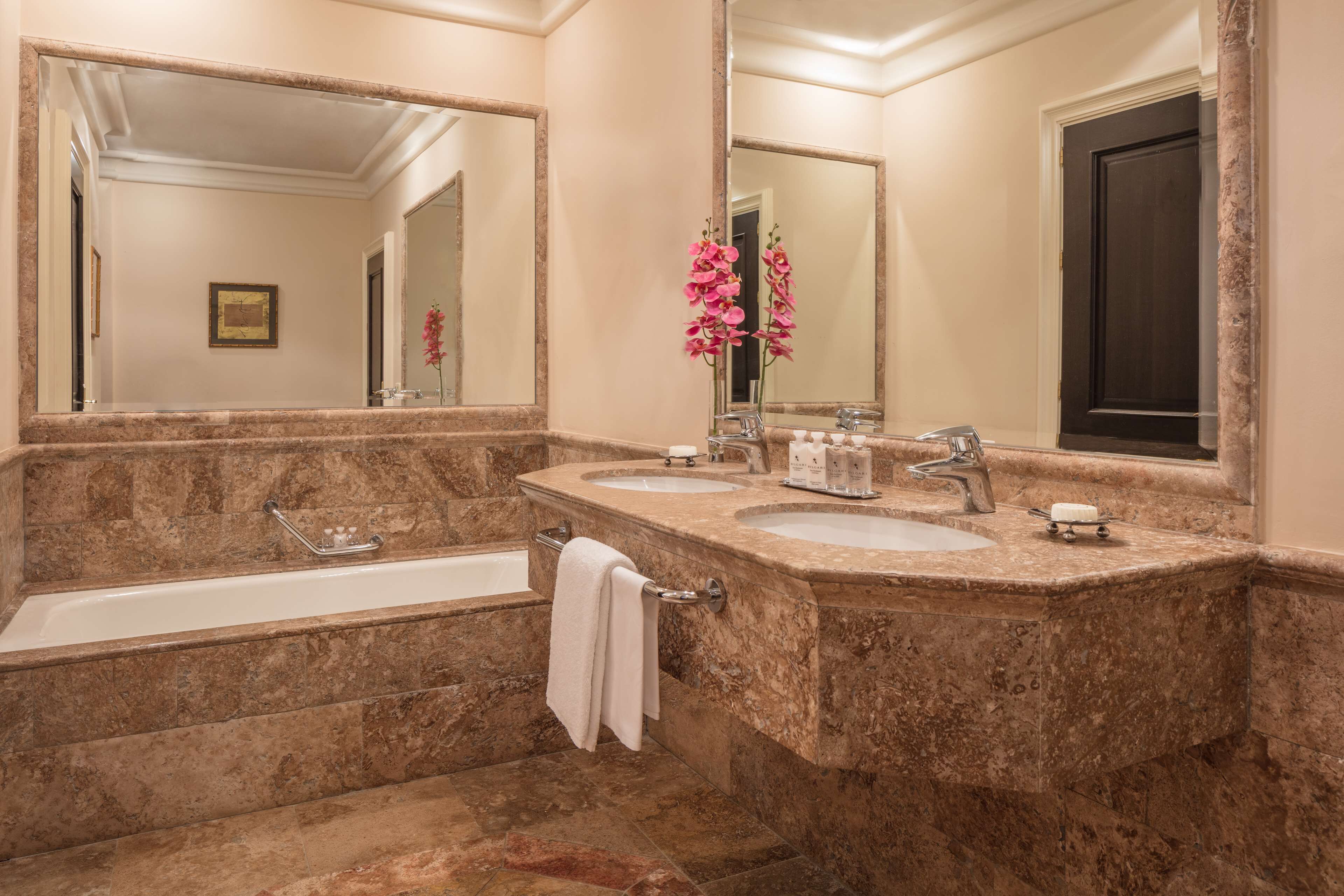 A bathroom with two sinks, a bathtub, and a large mirror.