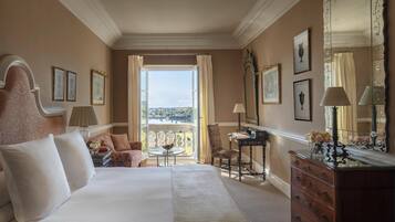 Une chambre d’hôtel avec un grand lit, un bureau, une chaise, une commode et un balcon avec vue.