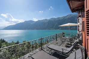 A balcony with outdoor furniture, a view of a lake, and mountains in the background. - Grandhotel Giessbach (Brienz)