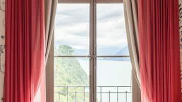 Un dormitorio con un ventanal grande, cortinas rojas y vistas a un paisaje montañoso.